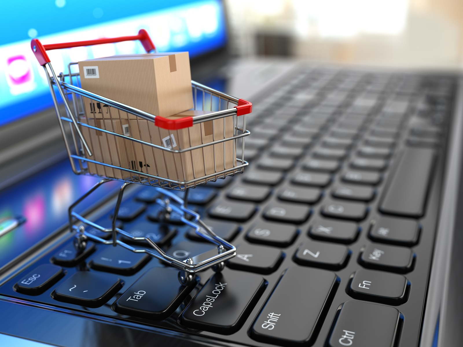 Carrinho de compras com caixas sobre teclado de notebook, representando o fulfillment para e-commerce